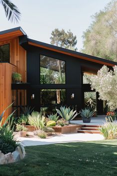 a black house with lots of plants in the front yard