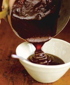 someone pouring chocolate sauce into a white bowl