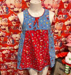 a mannequin wearing a red and blue dress in front of a wall full of teddy bears