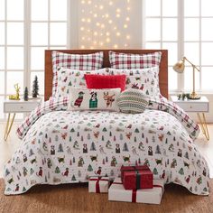 a christmas themed bed set with presents on the floor and lights in the window behind it