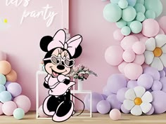 there is a wall with balloons and mickey mouse decorations in the corner, along with some flowers