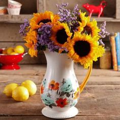 a white pitcher filled with yellow and purple flowers