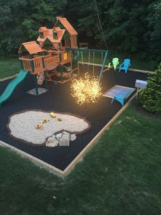 a play area with swings, slides and fire pit in the middle of it is lit up at night