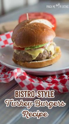 a hamburger sitting on top of a white plate next to a red and white checkered napkin