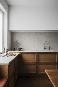 a kitchen with wooden cabinets and white counter tops, along with a sink that has no faucet