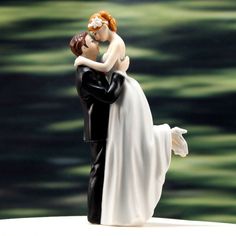 a bride and groom figurine on top of a white table with blurry background