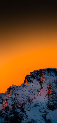 an airplane is flying over the top of a snow covered mountain at sunset or sunrise