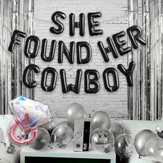 there is a sign that says she found her cowboy on the wall next to balloons