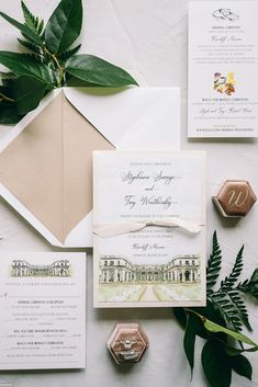 the wedding stationery is laid out on top of the table, with greenery