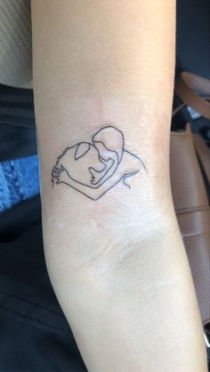 a small tattoo on the wrist of a woman's left arm, depicting a man holding a baby