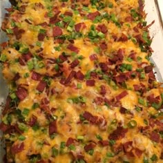 a casserole dish with cheese, green onions and bacon