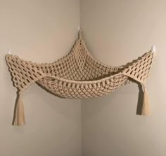 a crocheted hammock hanging on the wall with tassels attached to it