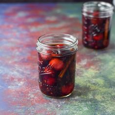 two jars filled with cherries sitting on top of a table