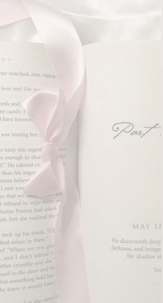 an open book with a pink ribbon on it