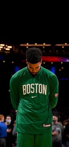 boston basketball player in green jersey standing on the court with his hands behind his back