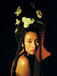 a woman with long braids and flowers in her hair is posing for the camera