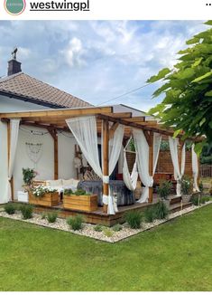 an outdoor living area with white drapes on the roof and curtains hanging over it