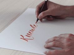 two hands are writing on a piece of paper