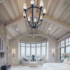 a bedroom with a large bed and lots of windows next to a fire place in the corner