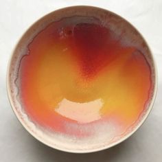 an orange and yellow bowl sitting on top of a white table