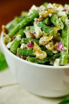 a white bowl filled with green beans and nuts