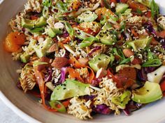 a white bowl filled with pasta salad and veggies on top of each other