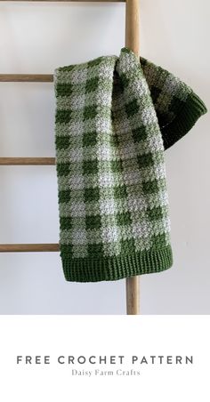 a green and white blanket hanging on a ladder with the text free crochet pattern