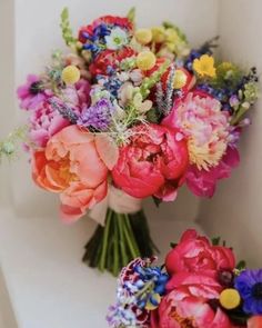 two bouquets of flowers sitting on top of a white shelf next to each other