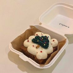 a cupcake with icing and decorations in a container on a white table top