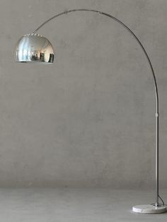 a floor lamp that is on top of a white table next to a gray wall