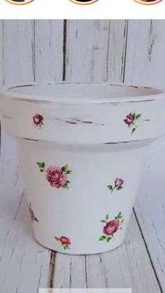 a white flower pot with pink roses painted on it