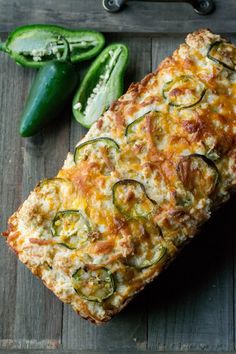 a loaf of zucchini bread on a cutting board next to some green peppers