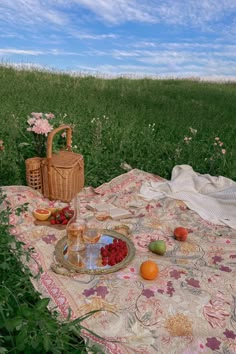 a picnic blanket with fruit on it in the middle of a field