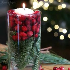 a candle that is on top of a table with berries and greenery in it