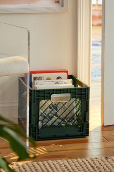 a green crate sitting on top of a hard wood floor next to a white door