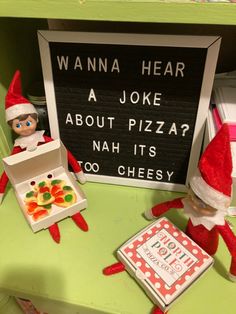 two elfs are sitting at a desk with pizza and candy in front of them