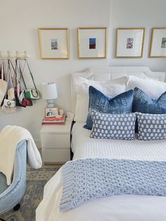 a bed with blue and white pillows on top of it next to a wall mounted pictures