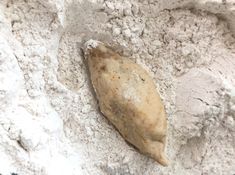 a piece of food sitting on top of a pile of white flour next to a spoon