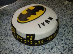 a batman themed birthday cake is on the counter with it's name written in black and yellow