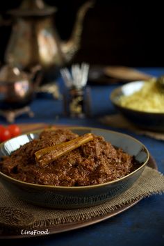 a bowl filled with food sitting on top of a blue table cloth next to a silver tea pot