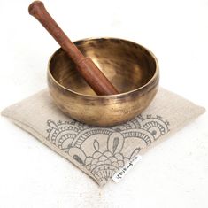 a metal bowl with a wooden spoon in it on top of a napkin next to a wood mallet