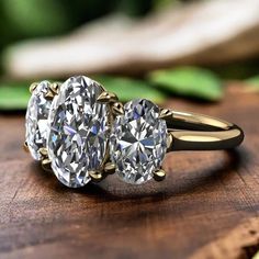 three stone diamond ring sitting on top of a wooden table