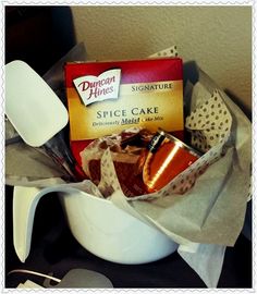 a cup filled with cake next to some spoons and a box of brownies