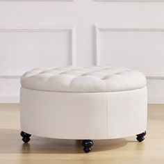 a white round ottoman sitting on top of a hard wood floor