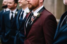 a group of men in suits and ties standing next to each other with one man wearing a boutonniere