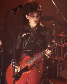 a woman in red tights playing guitar on stage