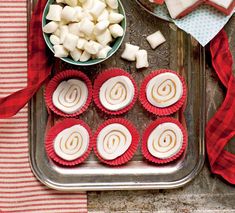 red and white cupcakes, marshmallows, and candy on a tray