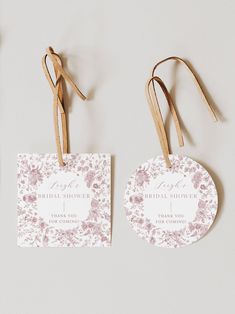 two tags with flowers on them hang from clothes pins