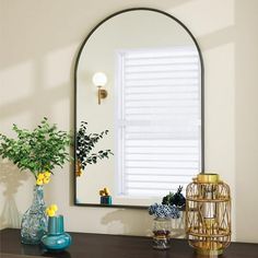 a mirror sitting on top of a wooden table next to a vase with flowers in it