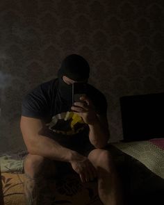 a man sitting on top of a bed holding a cell phone next to his face